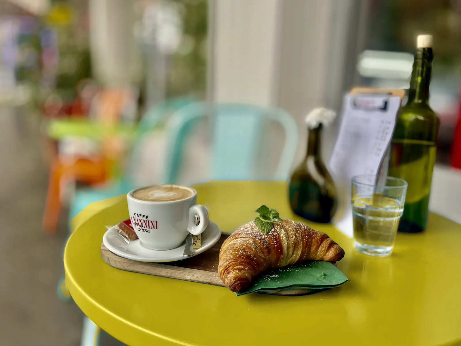 Kaffee und Croissant auf einem sonnengelben Tisch bei Amigo's