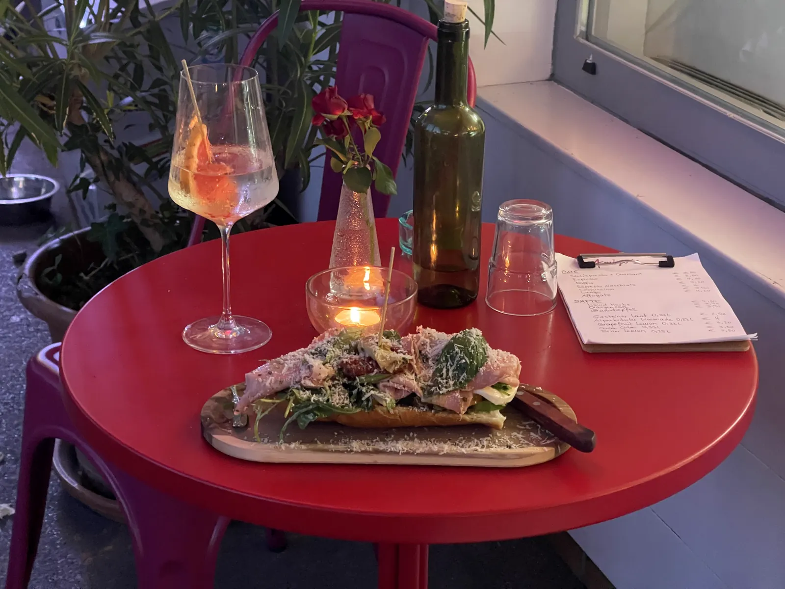 Roter Tisch bei Amigo's mit belegtem Brot, Getränk, Kerzenlicht und Blumen